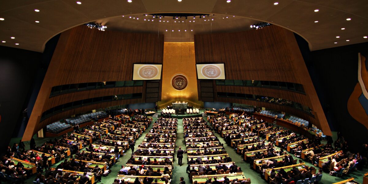 Flags of member nations hang in the UN General Assembly hall, symbolizing the global report on conflict-related sexual violence.