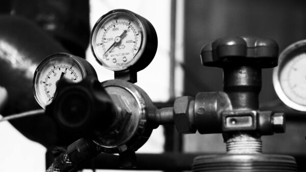 A close-up of a brass air pressure gauge showing kPa readings, symbolizing the debate over pressure as a temperature cause.