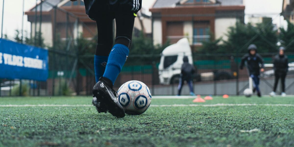 Young French footballers in red and blue jerseys training on a lush green pitch at a Clairefontaine academy, showcasing the French football talent factory.