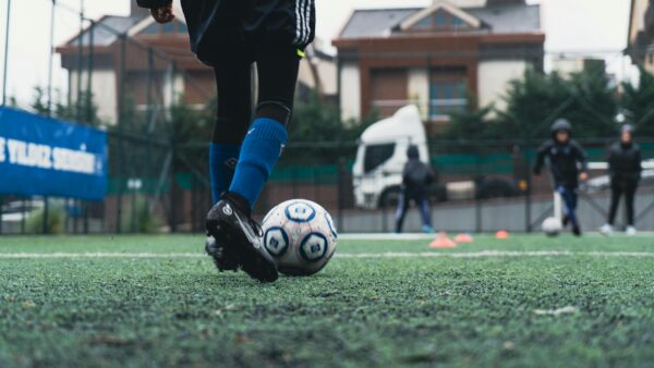 Young French footballers in red and blue jerseys training on a lush green pitch at a Clairefontaine academy, showcasing the French football talent factory.