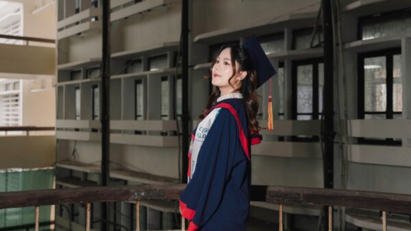 A graduating medical student in cap and gown speaks at a commencement podium, raising issues of health equity and war in her speech.