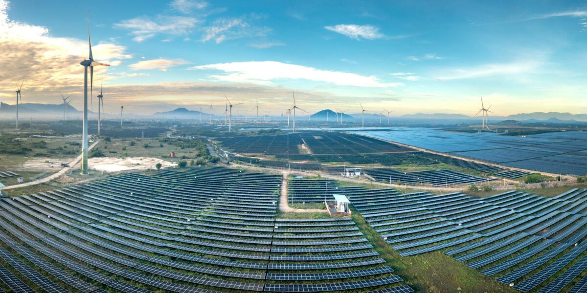 A landscape with wind turbines and solar panels at sunset, illustrating the rising cost of renewables in the UK energy transition.