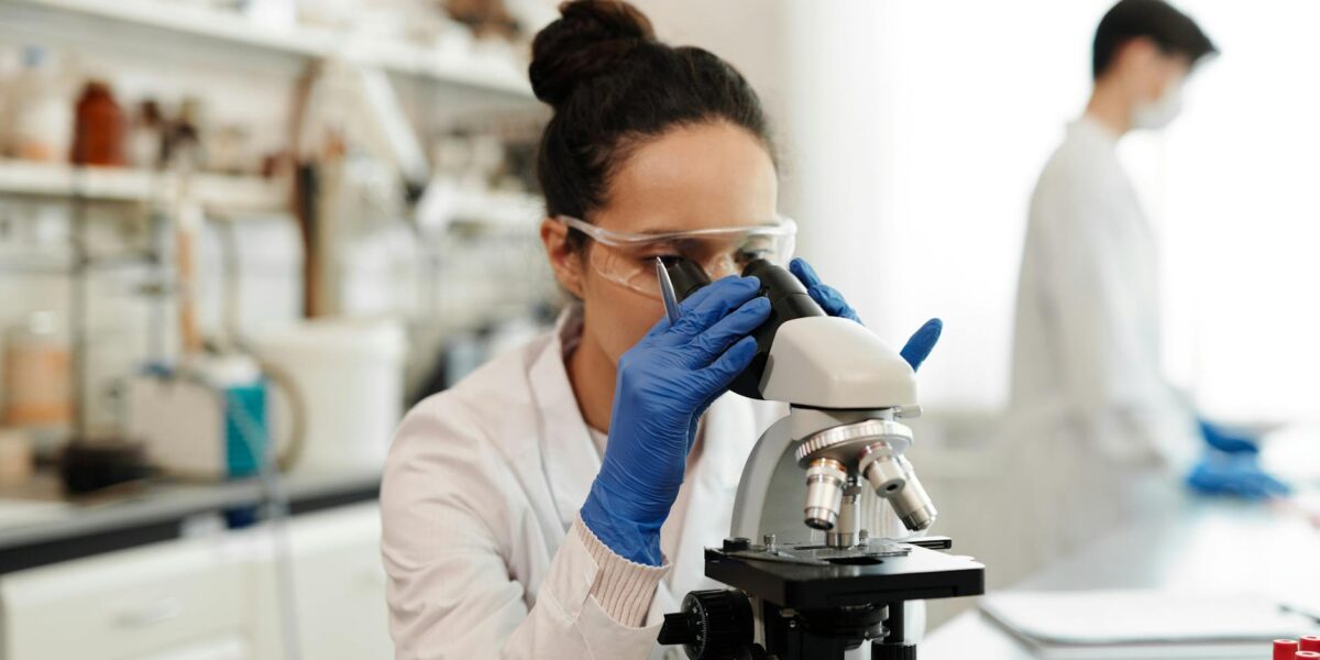 A scientist in a laboratory examining data on a tablet, surrounded by research equipment, illustrating the Willie Soon Exxon funding debate.