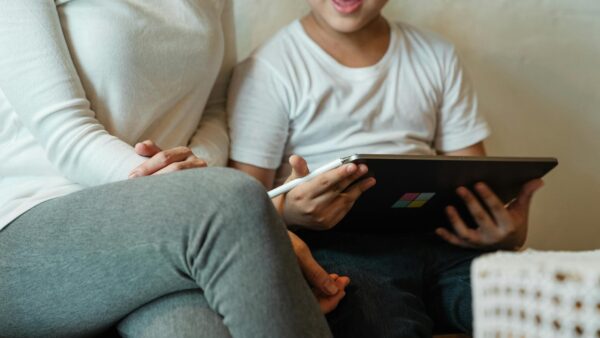 A young child using a tablet while a parent supervises, illustrating the need for child safety online in digital spaces.