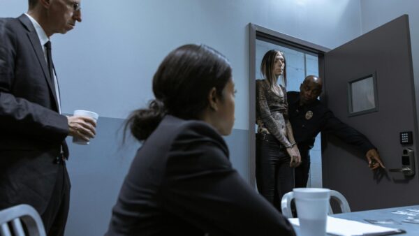 An ICE agent in handcuffs being led away by law enforcement, symbolizing the growing call for ICE agent accountability