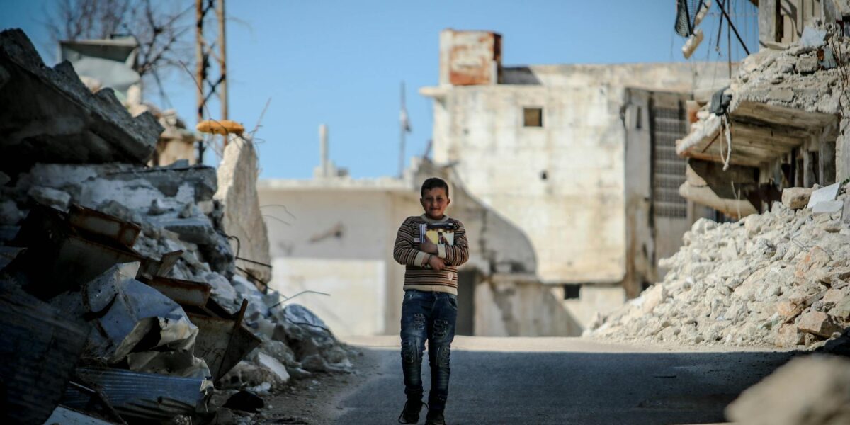 A young child sits on rubble in a Gaza street, illustrating the stark reality of Gaza children suffering amid the conflict.