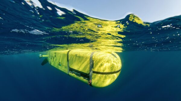 A sleek autonomous underwater drone gliding in deep blue ocean, representing the future of underwater drone tech for naval defense.