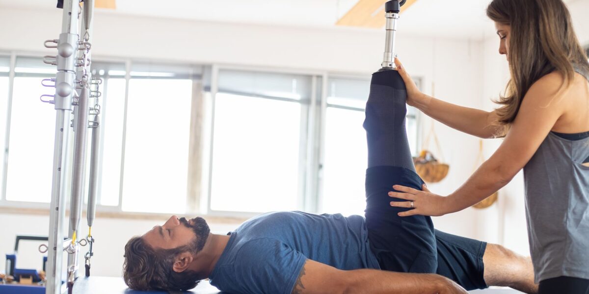 A patient in a hospital rehabilitation room working with a therapist on balance exercises due to rehab waiting lists