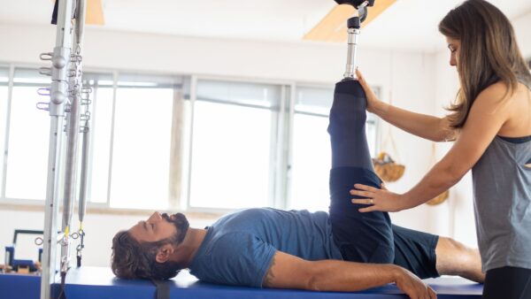 A patient in a hospital rehabilitation room working with a therapist on balance exercises due to rehab waiting lists
